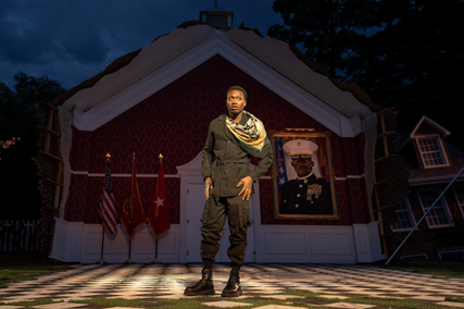 A person in military uniform standing in front of a building

Description automatically generated