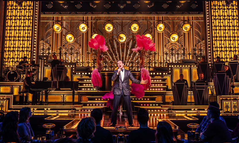 A person on stage with a microphone and a crowd of people watching
Description automatically generated