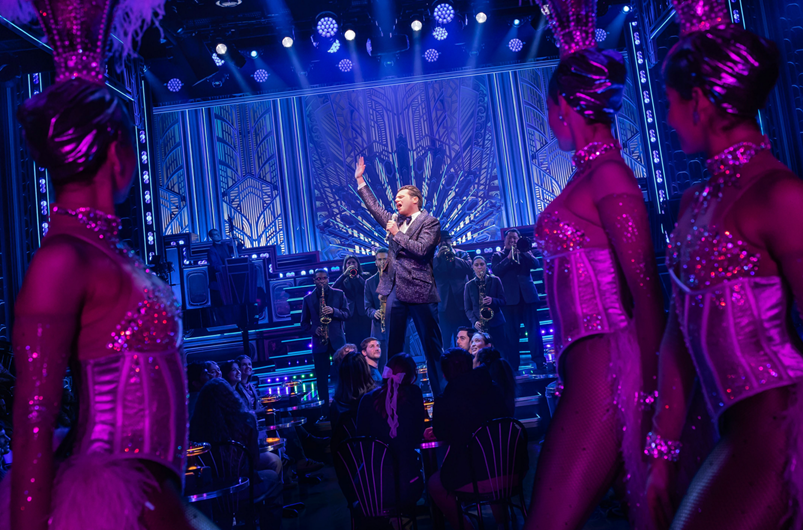 A person on a stage with a band in front of a crowd
Description automatically generated