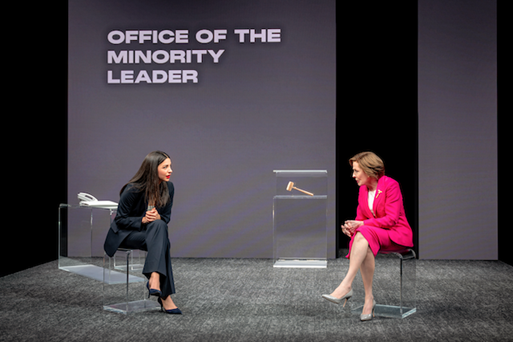 Two women sitting on chairs in front of a screen

Description automatically generated