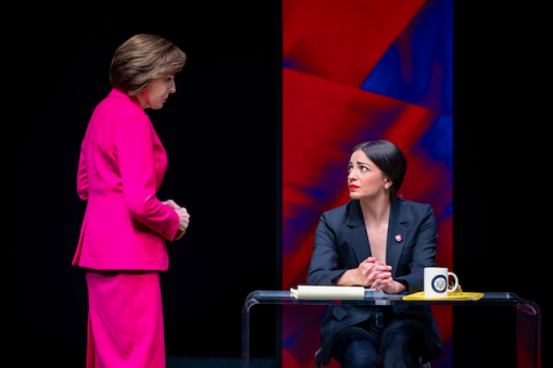 A person in a pink suit looking at another person in a suit Description automatically generated