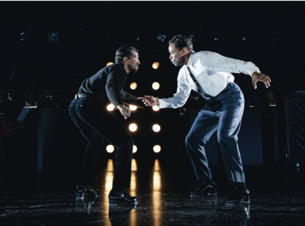 A person in a tie holding another person in a black shirt
Description automatically generated