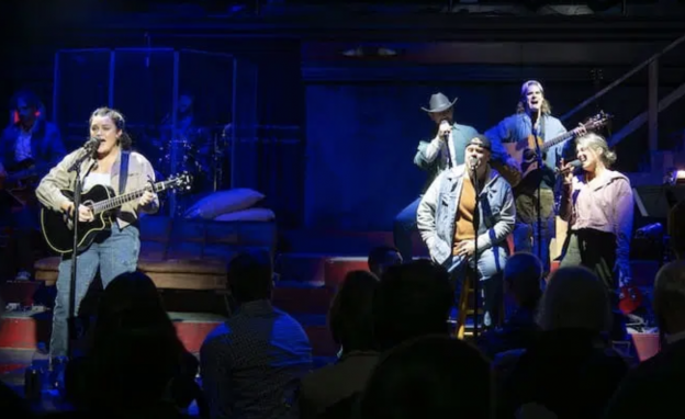A group of men on stage with microphones and guitars

Description automatically generated