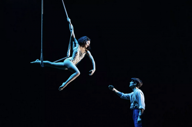 A person in a leotard from a rope

Description automatically generated