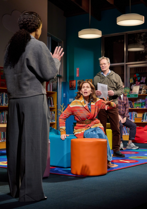 A person in a library with a person in a orange chair
Description automatically generated