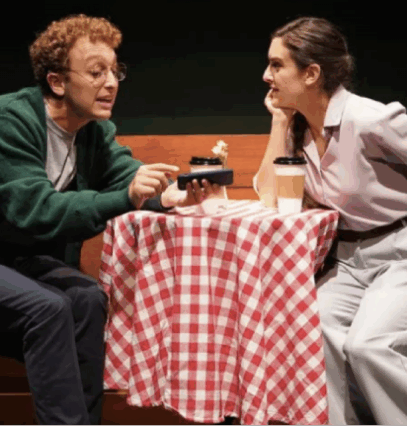 A person and person sitting at a table with a red and white checkered tablecloth

Description automatically generated