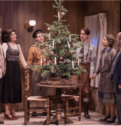 A group of people standing around a christmas tree

Description automatically generated
