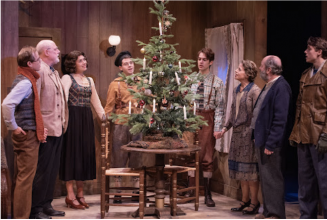 A group of people standing around a christmas tree Description automatically generated