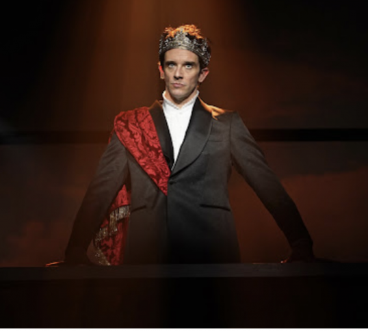 A person in a suit and crown

Description automatically generated