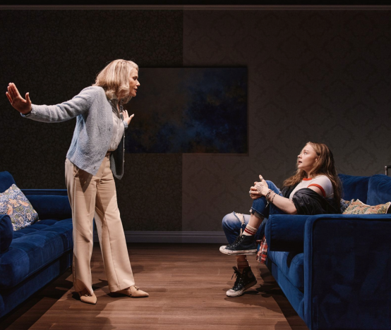 A person standing in front of a person sitting on a couch

Description automatically generated