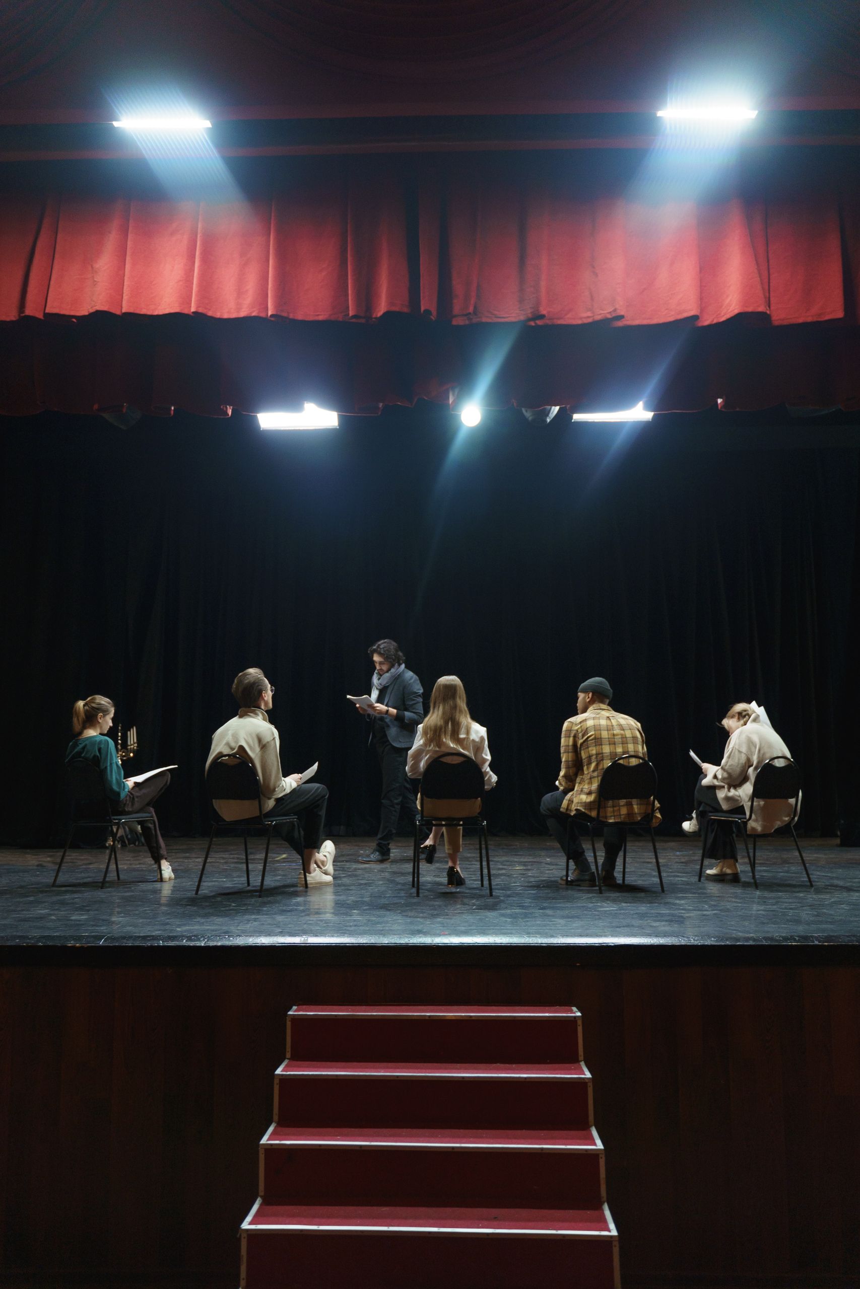 A group of actors rehearsing on stage under spotlights, creating an immersive theater experience.