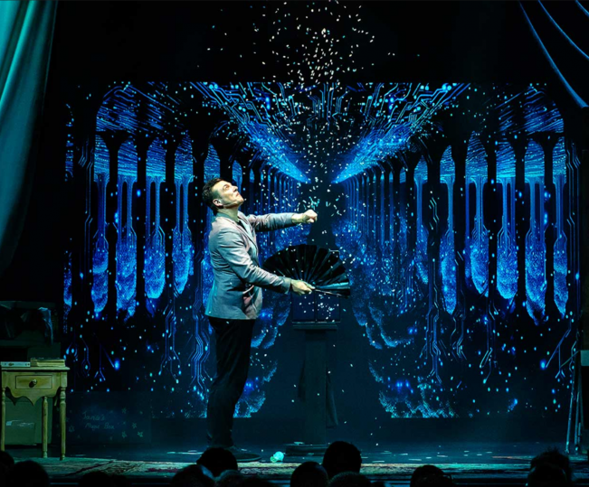 A person on a stage with a fan Description automatically generated