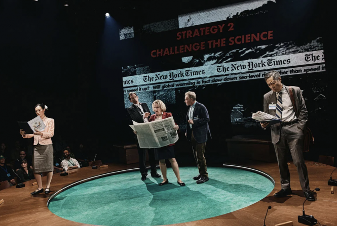 A group of people standing on a round green table Description automatically generated