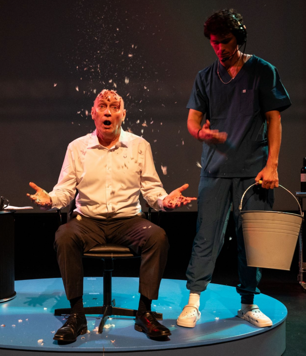A person sitting in a chair with a bucket in front of him Description automatically generated