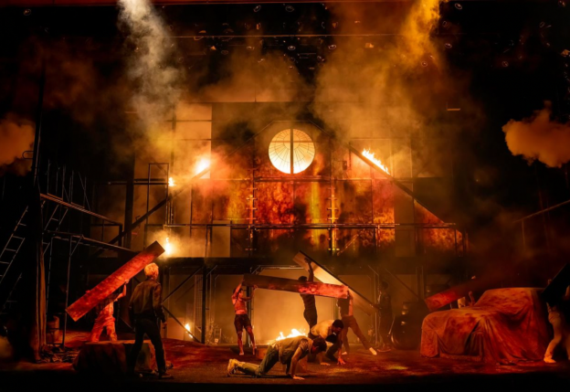 A group of people on a stage with smoke and fire Description automatically generated