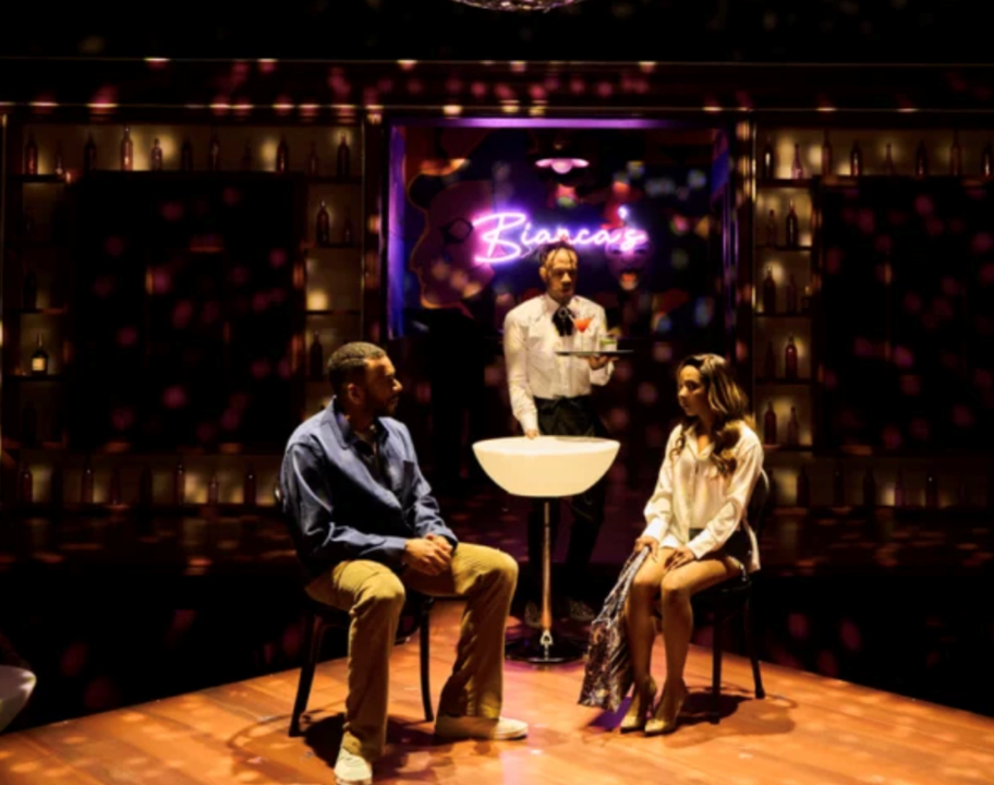 A person standing behind a person sitting on a stage
