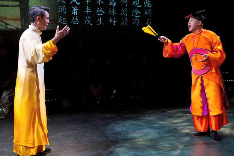 A person in orange and yellow robe holding paper fans