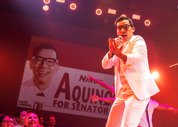 A person in a white suit singing on a stage