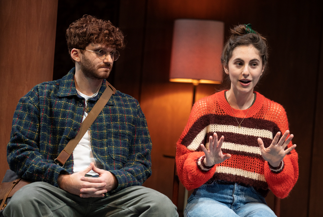 A person and person sitting on a stage