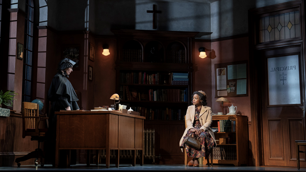 A person sitting in a chair next to a person in a room with bookshelves